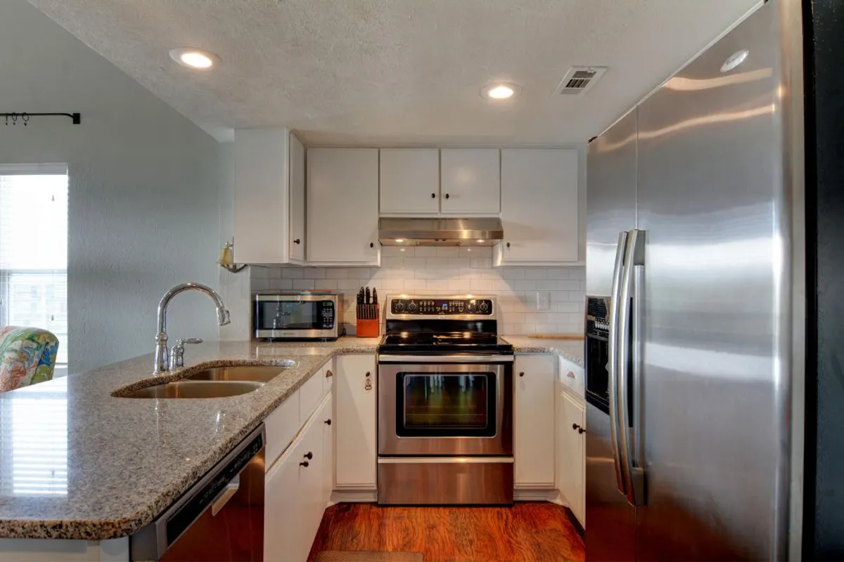 A modern kitchen view focusing on stainless steel appliances, granite countertops, and welcoming cabinetry, providing a slightly different angle than ec4ff9 and emphasizing space for cooking and socializing.